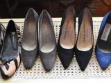 six pairs of women ' s shoes lined up in a row on a wicker chair