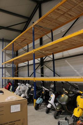 de nombreuses motos garées dans un entrepôt, avec des cartons par terre