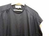 the back of a black shirt hanging on a hanger on a wall