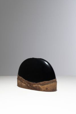 une sculpture en noir et blanc posée sur une surface blanche, avec un fond gris