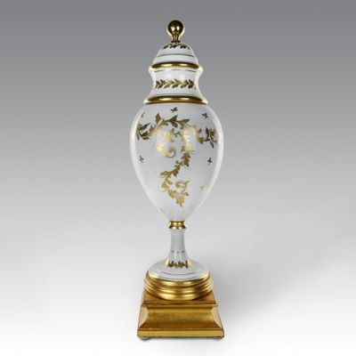a white and gold vase sitting on top of a wooden base
