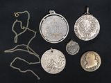 several different types of silver coins and pendants on a black surface