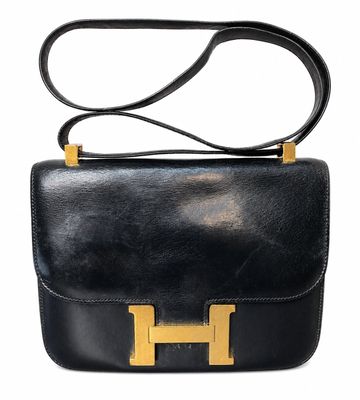 a black leather handbag with gold hardware on a white background
