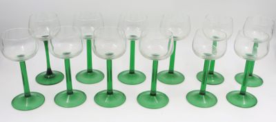 six verres à vin verts sont alignés sur une surface blanche