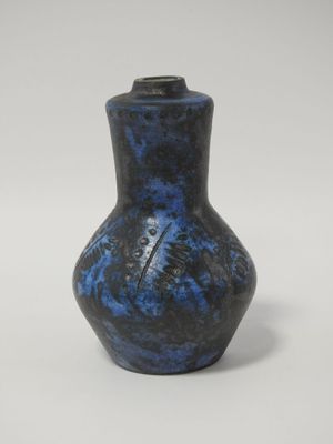 un vase bleu et noir posé sur une surface blanche