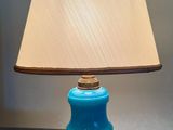 une lampe de table bleue surmontée d'un abat-jour beige