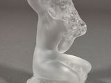 une sculpture en verre représentant une femme assise sur une table