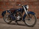 a blue motorcycle that is parked in front of a brick wall