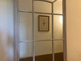 un miroir sur le mur au-dessus d'un lavabo dans une salle de bains