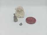 une petite figurine représentant une femme assise à côté d'un cachet de cire et d'un tampon de cire