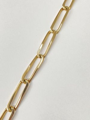 a close up of a gold chain bracelet on a white surface