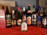 many bottles of alcohol on a table with a red cloth