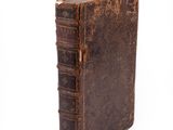 an old book is sitting on top of a white surface