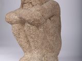 statue of a man with a hat on his head sitting on a white surface