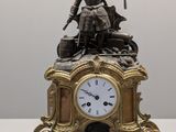 une horloge surmontée d'une statue, posée sur une table