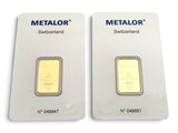 two gold bars are sitting side by side on a white surface