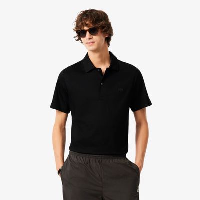 un homme vêtu d'un polo noir et d'un pantalon gris
