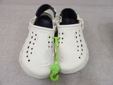 pair of white crocs shoes with a green hook on the sole