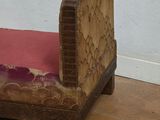 a small wooden bed with a pink pillow on it