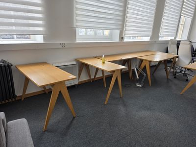 three desks in the corner of a room with a radiator in the corner