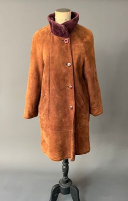 un manteau marron posé sur un pied de mannequin, sur un fond gris
