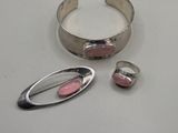 two pieces of silver and pink enamel on a white surface
