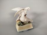une figurine représentant un oiseau blanc perché sur un livre