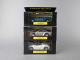 three toy cars are in a box on a white surface