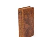 an old book with a brown cover sitting on top of a white surface