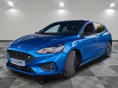 Une Ford Focus bleue est garée dans une grande pièce