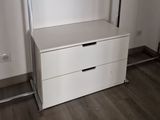 an image of a white chest of drawers in the corner of a room