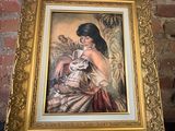 un tableau représentant une femme tenant un bébé dans ses bras, dans un cadre doré