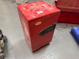 a small red refrigerator sitting on the floor in a room