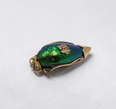 une breloque en forme de scarabée dorée et verte, avec une base plaquée or