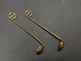 a pair of brass spoons on a black surface
