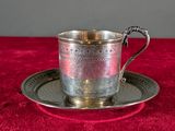 a silver cup and saucer on a red table cloth