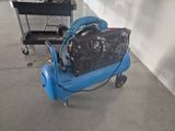 a blue air compressor sitting on the floor next to a cart