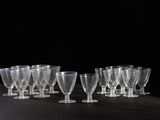 six verres à vin transparents sont alignés sur une surface noire