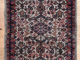 a close up of a red and black rug on a wooden floor