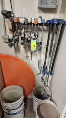 several buckets of paint are lined up against a wall