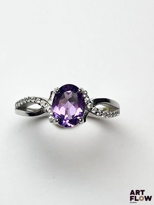 un gros plan d'une bague sertie d'une pierre violette et de diamants