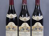 three bottles of red wine sitting on top of a glass table