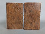 two old books sitting on top of a table next to each other