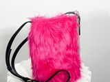 un sac à main rose en fourrure posé sur un socle blanc