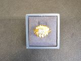 une bague en or dans une boîte blanche posée sur une surface grise