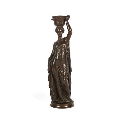 une statue en bronze représentant une femme portant un pot sur la tête