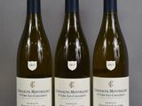 three bottles of white wine are lined up on a table