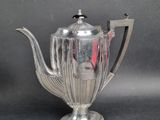 an antique silver tea pot with a red handle on a black background