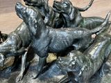 statue représentant un groupe de chiens courant sur un rocher, avec un chien en arrière-plan
