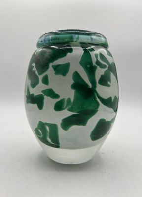 un vase vert et blanc posé sur une surface blanche